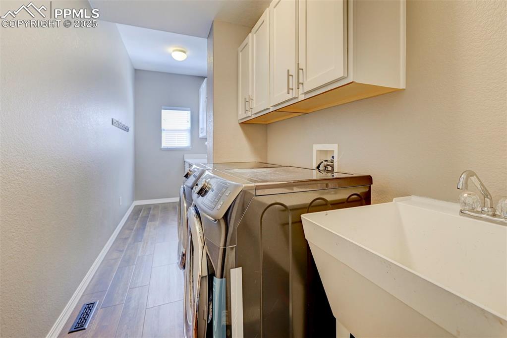 Image 16 of 31: Washroom with a sink, washing machine and dryer, baseboards, wood finished 