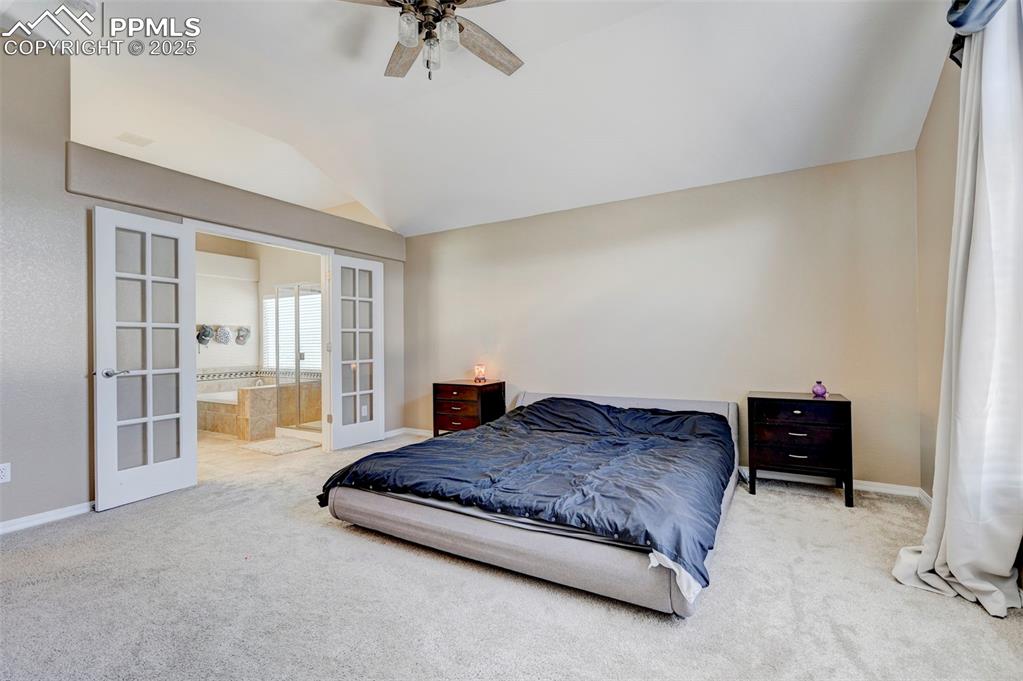 Image 17 of 31: Carpeted bedroom with connected bathroom, ceiling fan, french doors, basebo