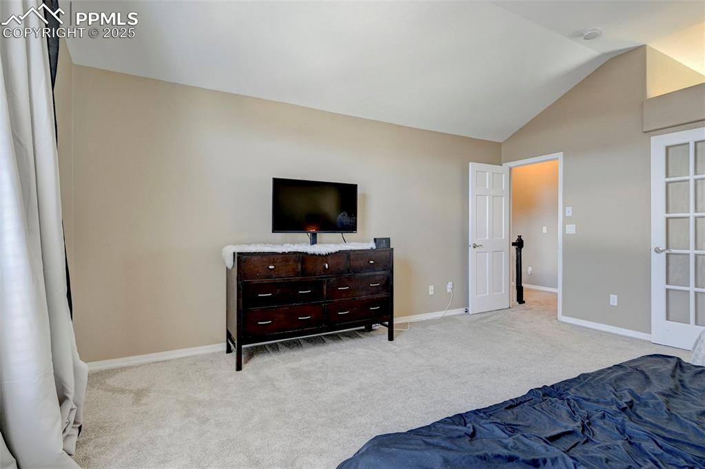 Image 18 of 31: Carpeted bedroom with lofted ceiling and baseboards