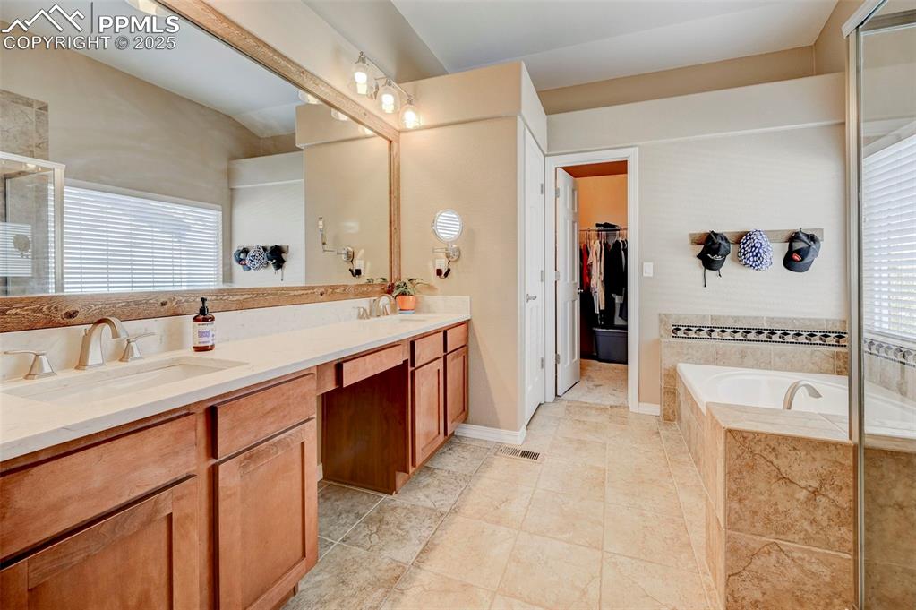 Image 19 of 31: Bathroom with a walk in closet, double vanity, a bath, and a sink