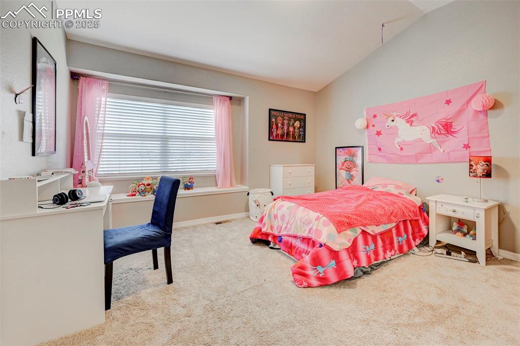 Image 21 of 31: Carpeted bedroom featuring lofted ceiling, baseboards, and visible vents