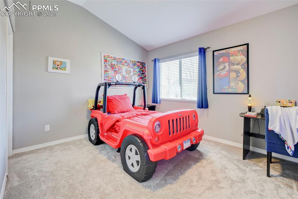 Image 23 of 31: Carpeted bedroom featuring vaulted ceiling and baseboards