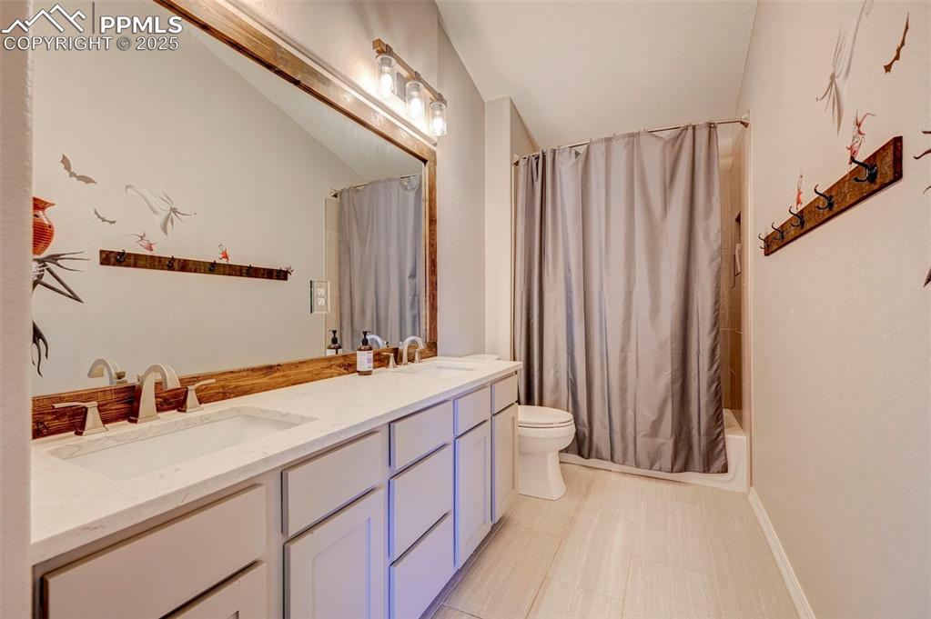 Image 27 of 31: Full bathroom featuring double vanity, toilet, shower / bath combo, and a s