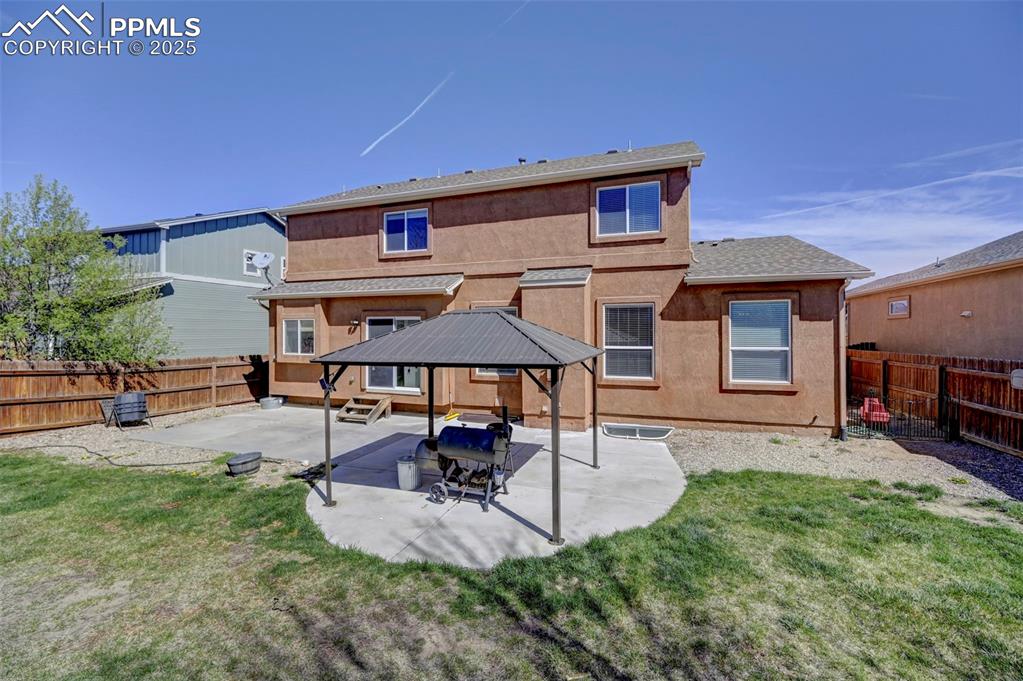Image 31 of 31: Back of property with a fenced backyard, a gazebo, a patio area, and a yard