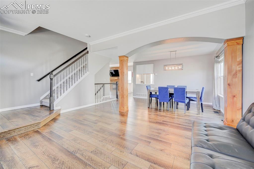 Image 4 of 31: Living room featuring stairs, arched walkways, light wood-style flooring, b