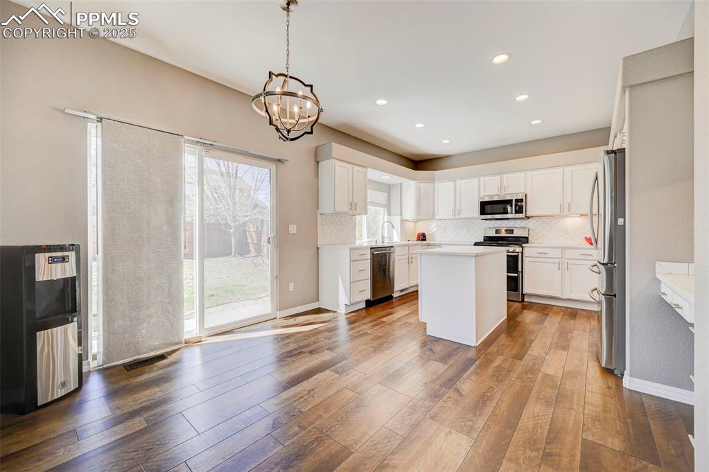 Image 6 of 31: Kitchen featuring stainless steel appliances, a center island, dark wood-st