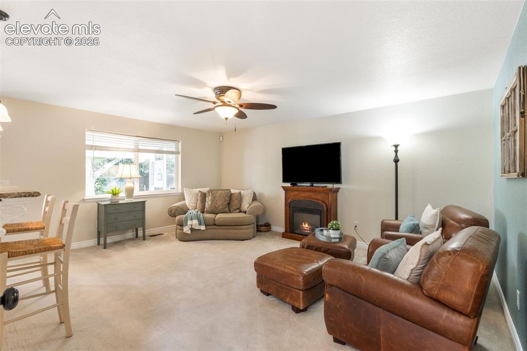 Image 15 of 47: Living room with carpet, ceiling fan and window. A bar height pony wall div