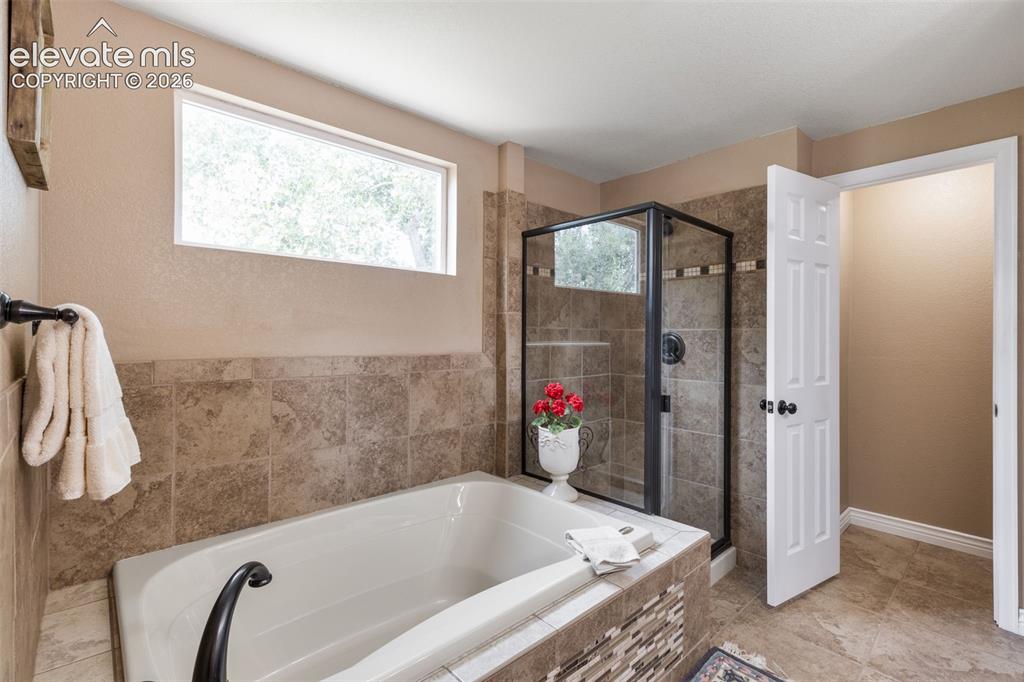 Image 22 of 47: En suite 5 piece primary bathroom with natural light, soaking tub, walk-in 