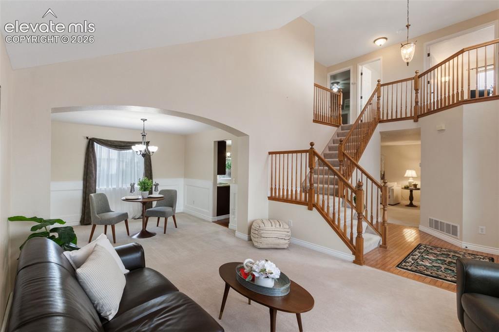 Image 4 of 50: Living off entryway with dramatic staircase and hardwood floor.