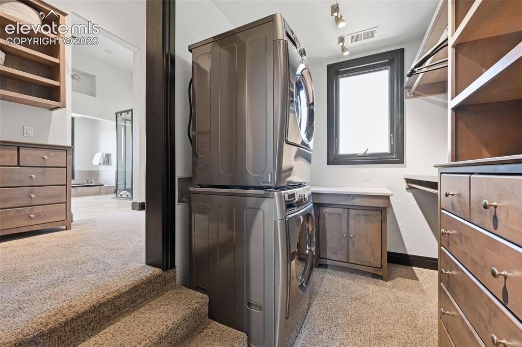 Image 27 of 48: Custom his and hers master closets with included washer and dryer!