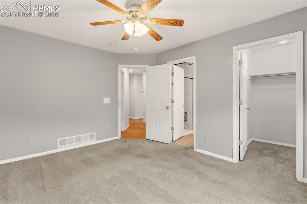Image 12 of 27: Master bedroom featuring a walk in closet, light carpet, ensuite bathroom, 