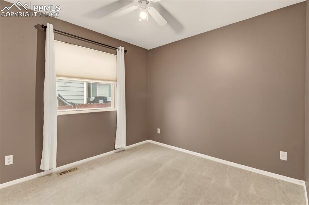 Image 15 of 27: Bedroom 2 with light colored carpet and ceiling fan