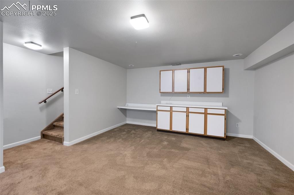 Image 23 of 39: Family room in basement with cupboard storage