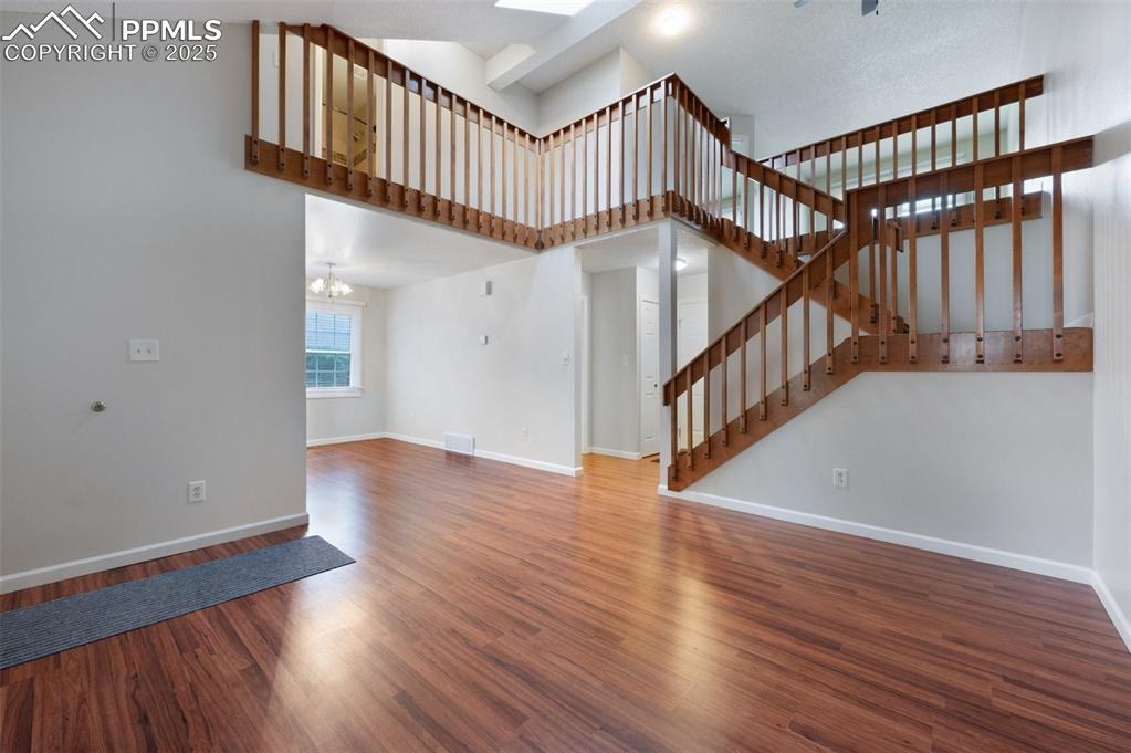 Image 4 of 39: Open living room with warm wood-like flooring