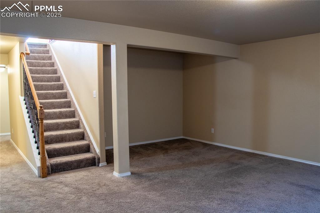 Image 18 of 31: Finished basement with carpet flooring and stairway