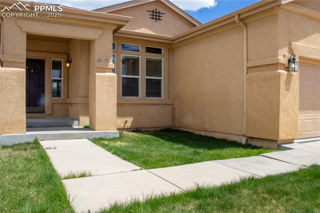 Image 2 of 31: View of exterior entry featuring stucco siding and a garage