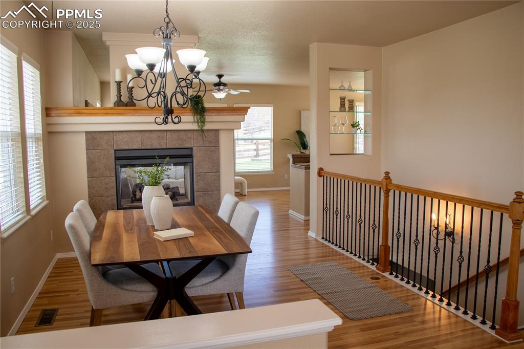 Image 3 of 31: Dining room featuring wood finished floors, a chandelier, a fireplace, and 