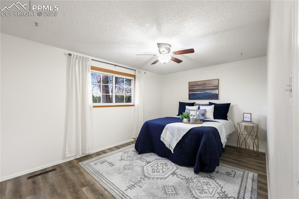Image 14 of 32: Bedroom with a textured ceiling, wood finished floors, and ceiling fan