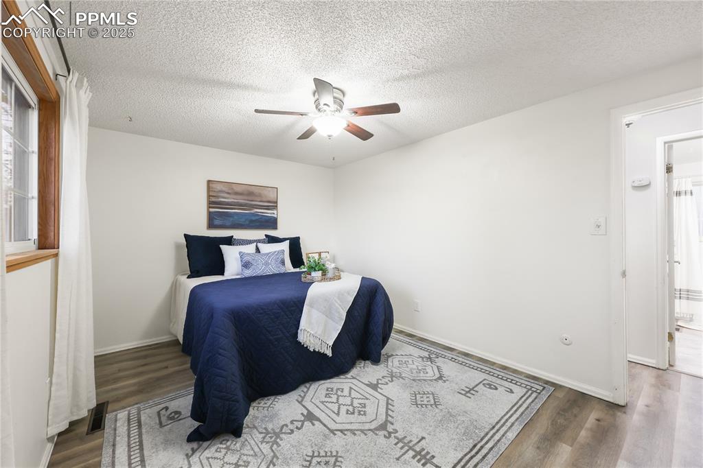 Image 15 of 32: Bedroom with wood finished floors, ceiling fan, and a textured ceiling