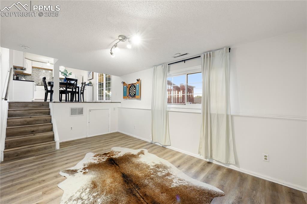 Image 17 of 32: Unfurnished living room featuring a textured ceiling, light wood-type floor