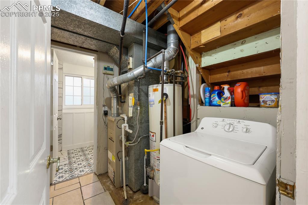 Image 24 of 32: Laundry area featuring washer / dryer, water heater, light tile patterned f