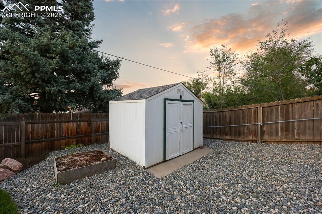 Image 31 of 32: View of shed with a fenced backyard and a vegetable garden