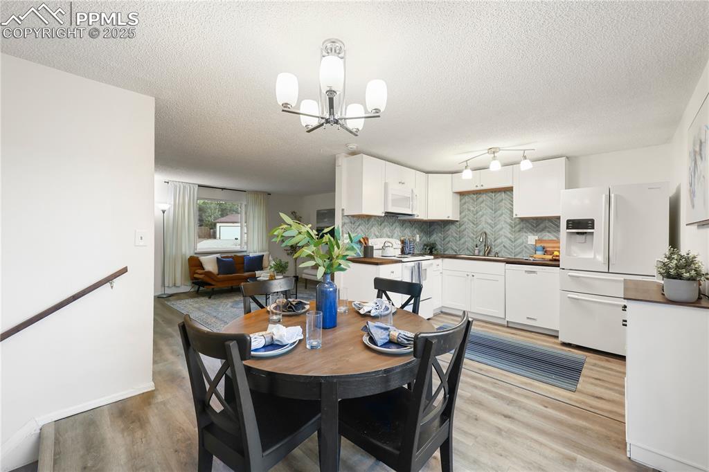 Image 6 of 32: Dining room featuring light wood-style floors, a textured ceiling, and a ch