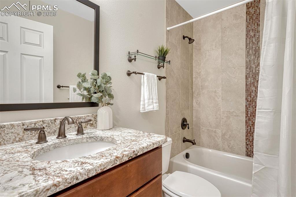 Image 17 of 50: Main Level full bathroom with beautiful tile and light granite countertop.