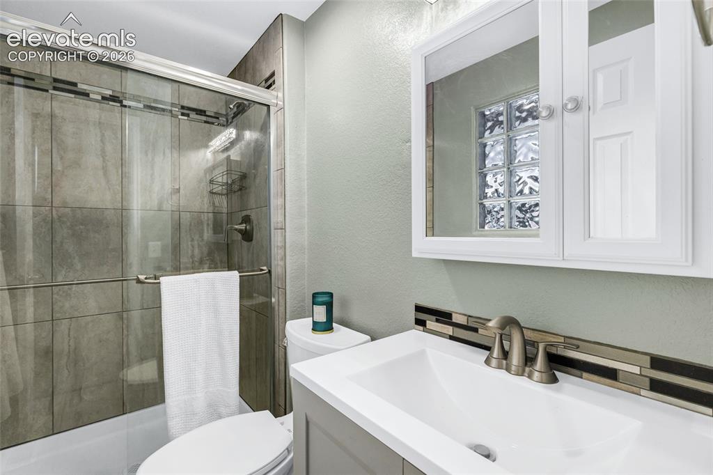 Image 16 of 46: Walk-in shower with full-height tile surround and sliding glass enclosure