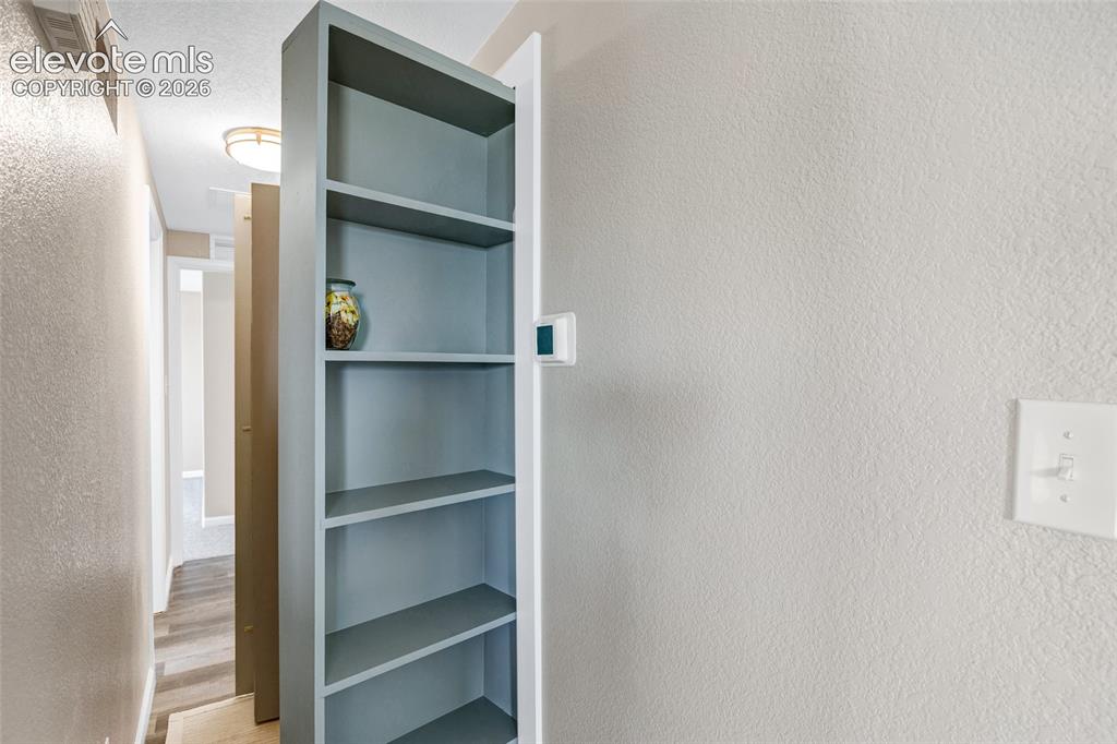 Image 19 of 46: Hallway featuring wood-finish flooring, built-in shelving, neutral-toned wa