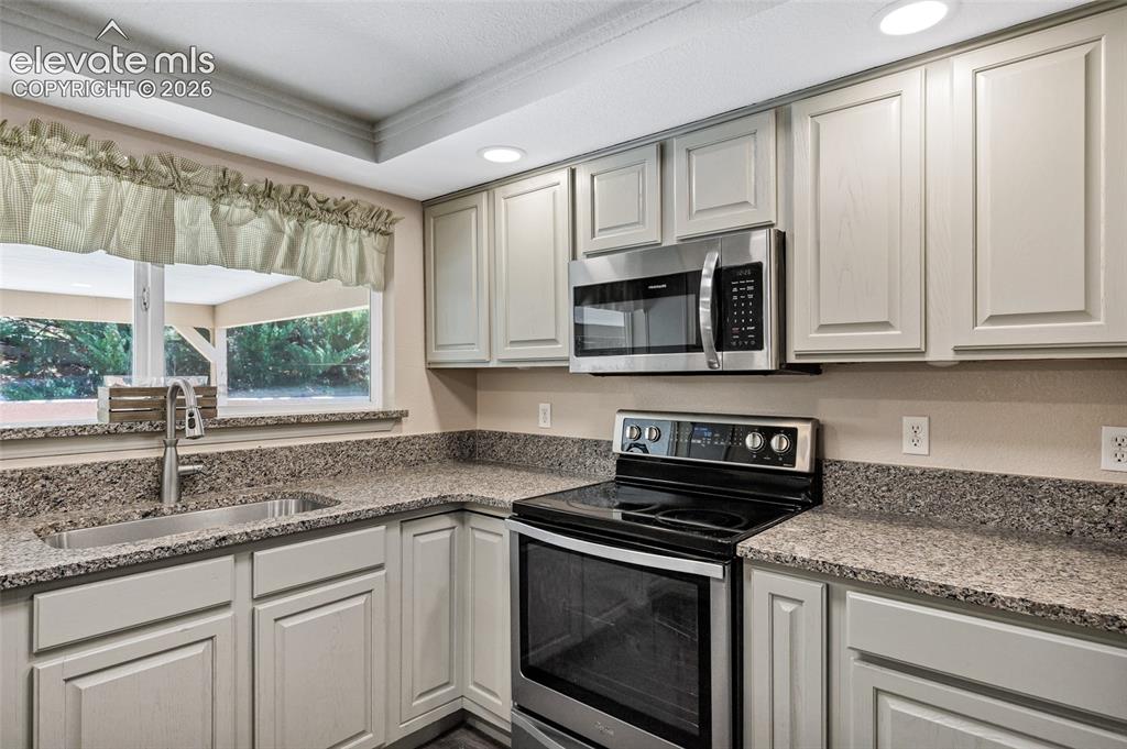 Image 9 of 46: Kitchen walk-out slider to patio featuring an extended island with stone-lo