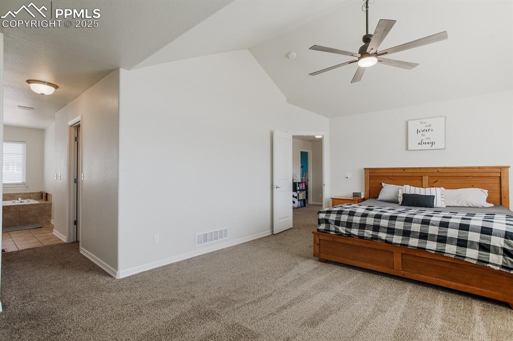 Image 23 of 49: Bedroom featuring high vaulted ceiling, ensuite bath, visible vents, carpet