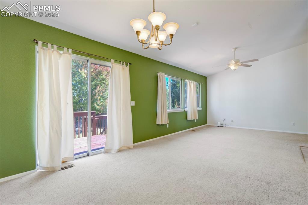Image 12 of 50: Carpeted spare room with a chandelier and ceiling fan