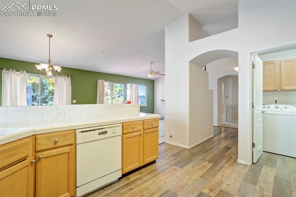 Image 16 of 50: Kitchen featuring washer / dryer, arched walkways, white dishwasher, light 