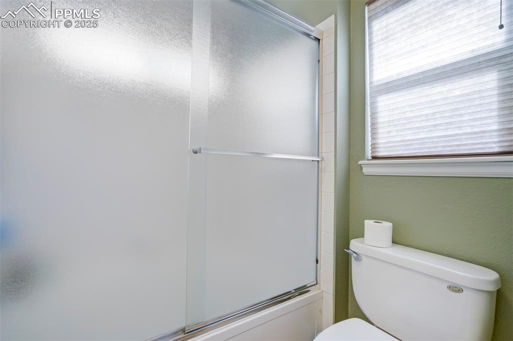Image 28 of 50: Full bath featuring toilet and combined bath / shower with glass door