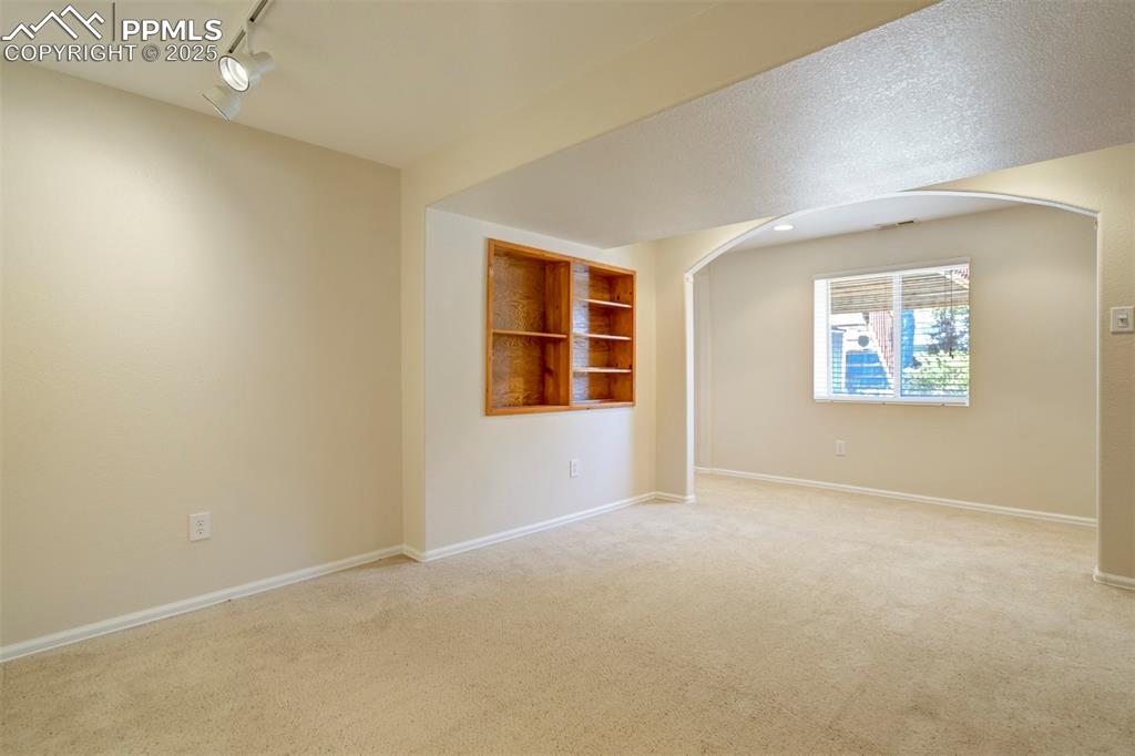 Image 39 of 50: Carpeted empty room featuring track lighting and arched walkways