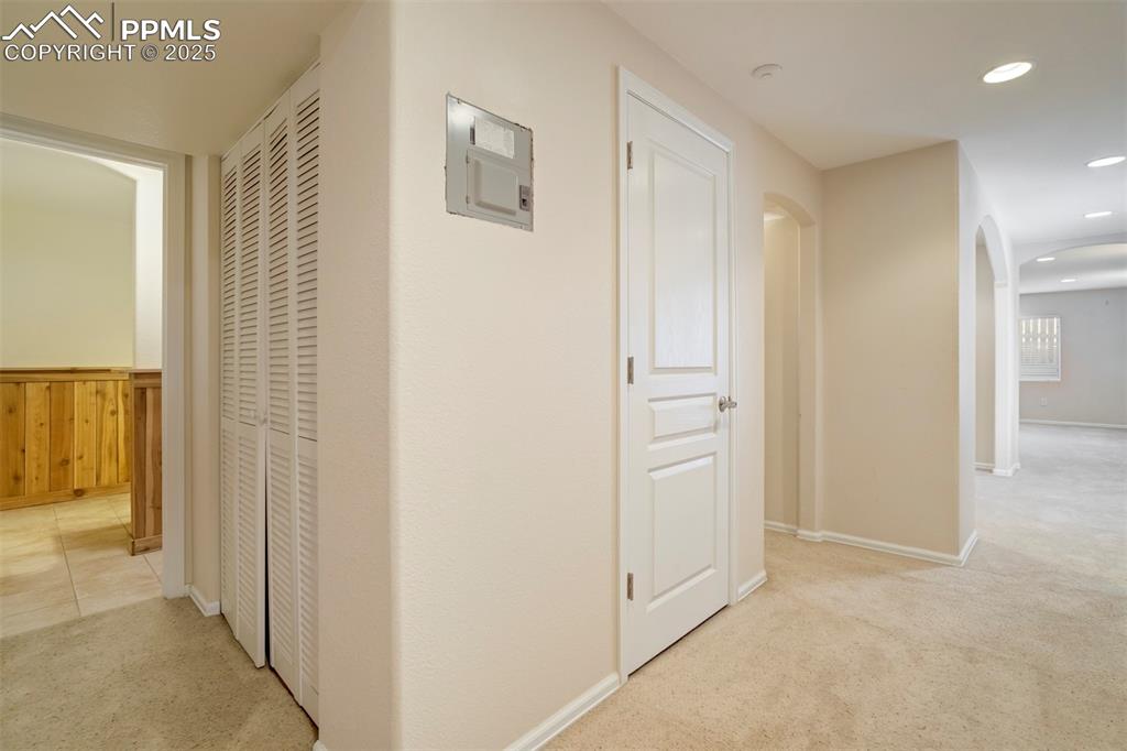 Image 40 of 50: Hallway with arched walkways, light colored carpet, recessed lighting, and 