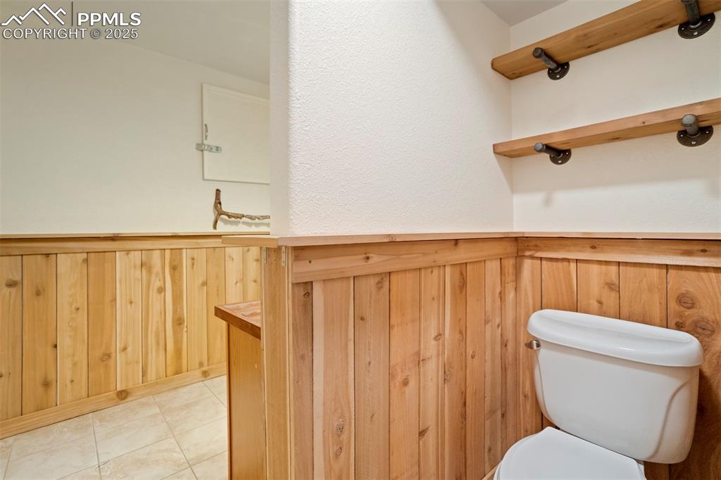 Image 41 of 50: Bathroom with wooden walls, a wainscoted wall, and light tile patterned flo