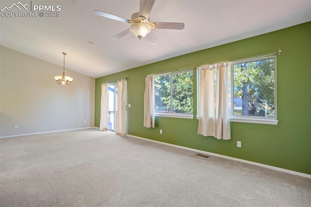 Image 9 of 50: Empty room featuring carpet flooring, a ceiling fan, a chandelier, and vaul