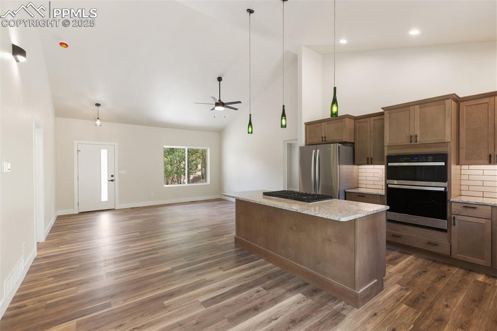 Image 11 of 35: Kitchen featuring high vaulted ceiling, pendant lighting, tasteful backspla