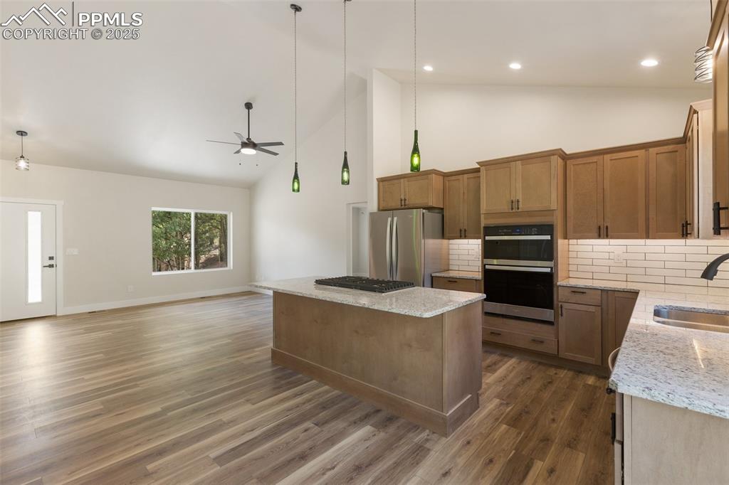 Image 13 of 35: Kitchen featuring high vaulted ceiling, tasteful backsplash, hanging light