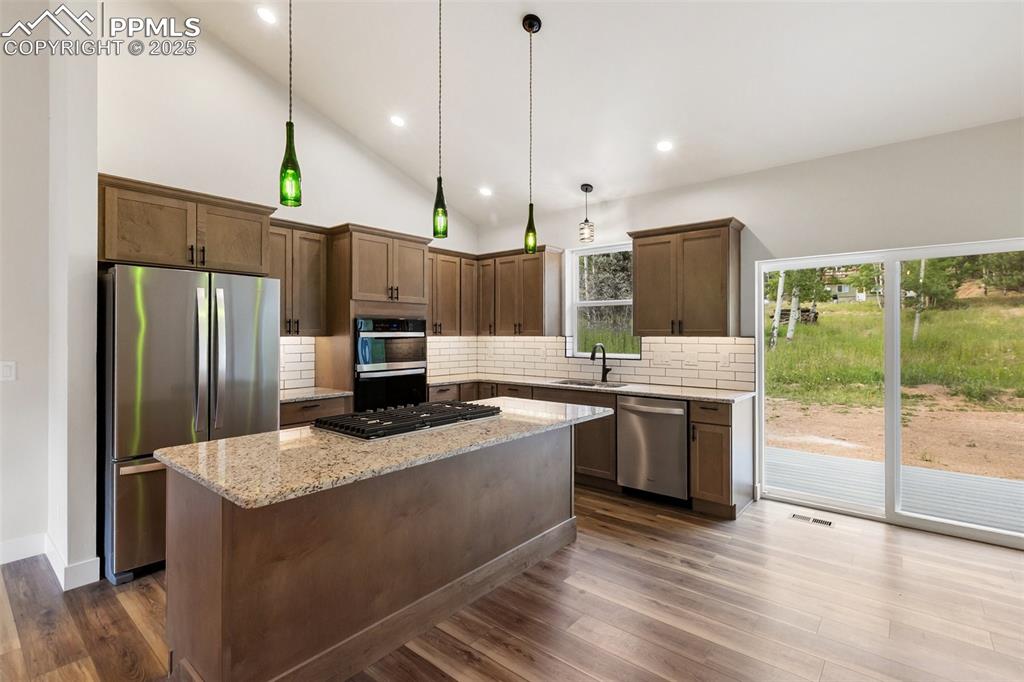 Image 14 of 35: Kitchen featuring appliances with stainless steel finishes, light stone cou
