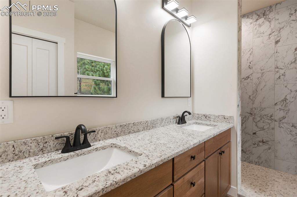 Image 22 of 35: Bathroom featuring double vanity and tiled shower