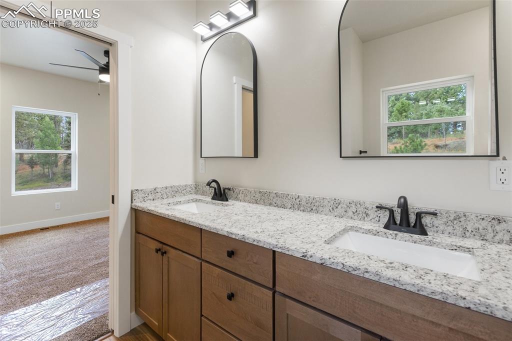 Image 24 of 35: Bathroom with double vanity and a ceiling fan