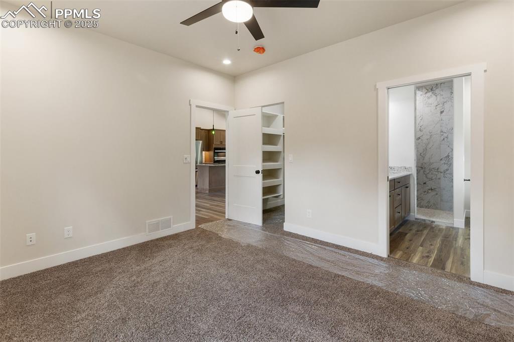 Image 26 of 35: Unfurnished bedroom with dark carpet, connected bathroom, recessed lighting