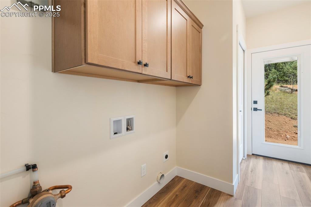 Image 27 of 35: Laundry area with light wood finished floors, washer hookup, cabinet space,