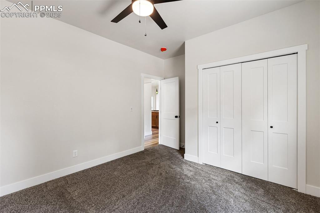 Image 29 of 35: Unfurnished bedroom with dark carpet, a closet, and a ceiling fan