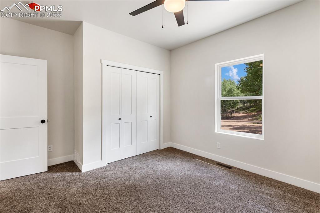 Image 30 of 35: Unfurnished bedroom with dark carpet, a closet, and ceiling fan