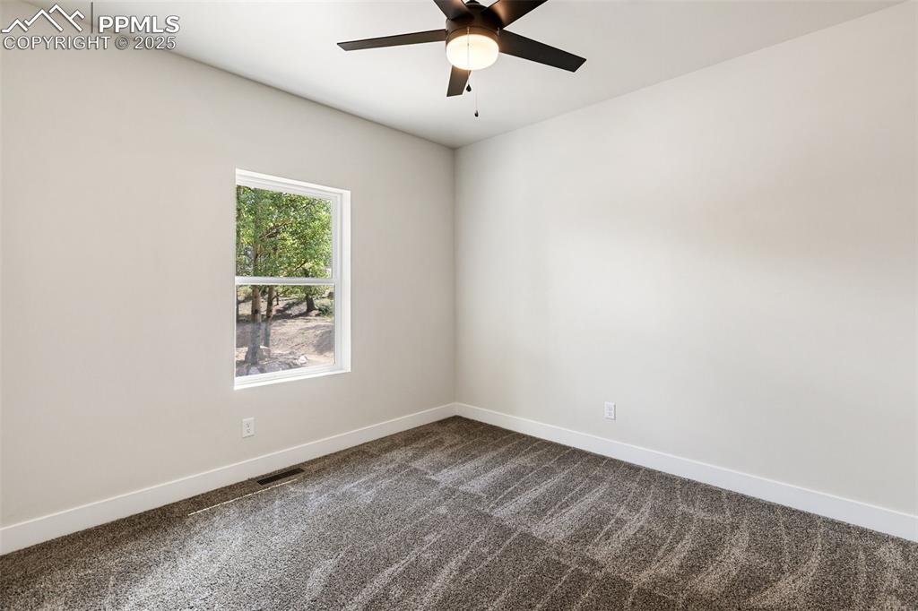Image 31 of 35: Spare room featuring dark colored carpet and a ceiling fan