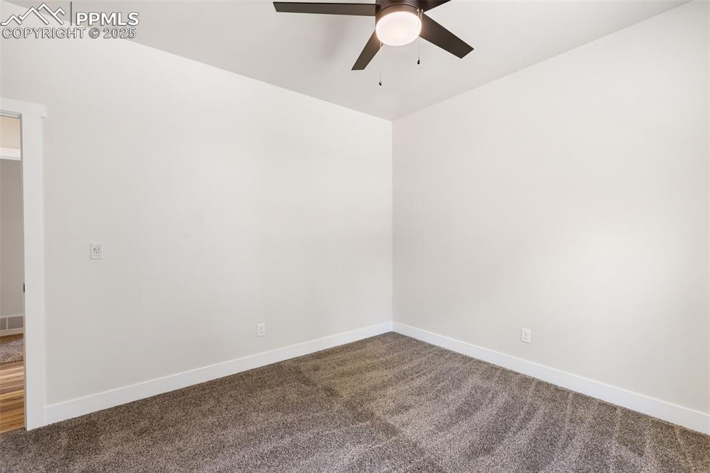 Image 33 of 35: Spare room featuring dark carpet and a ceiling fan